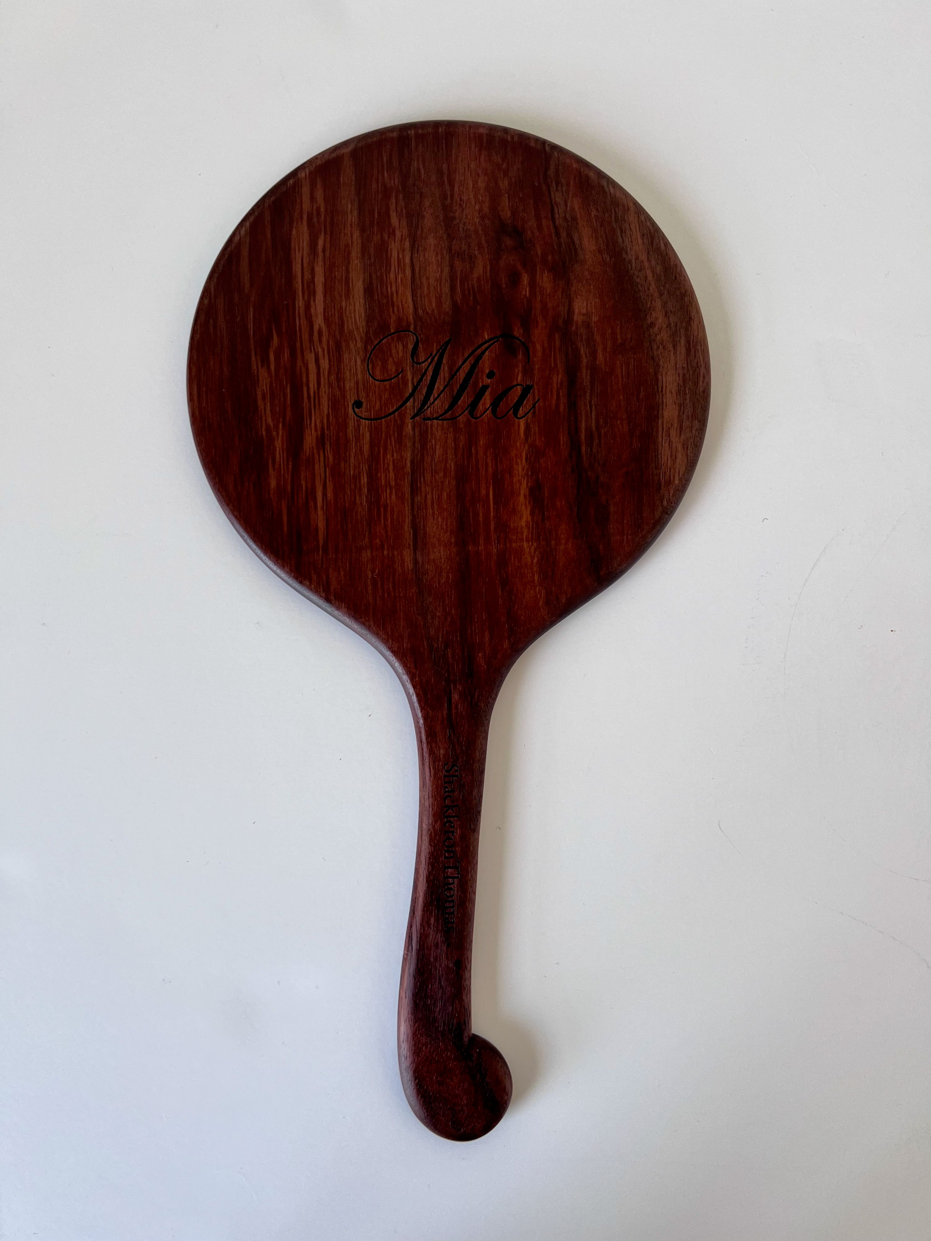 back-side of a hand-carved mirror with a scrolled handle and carved name