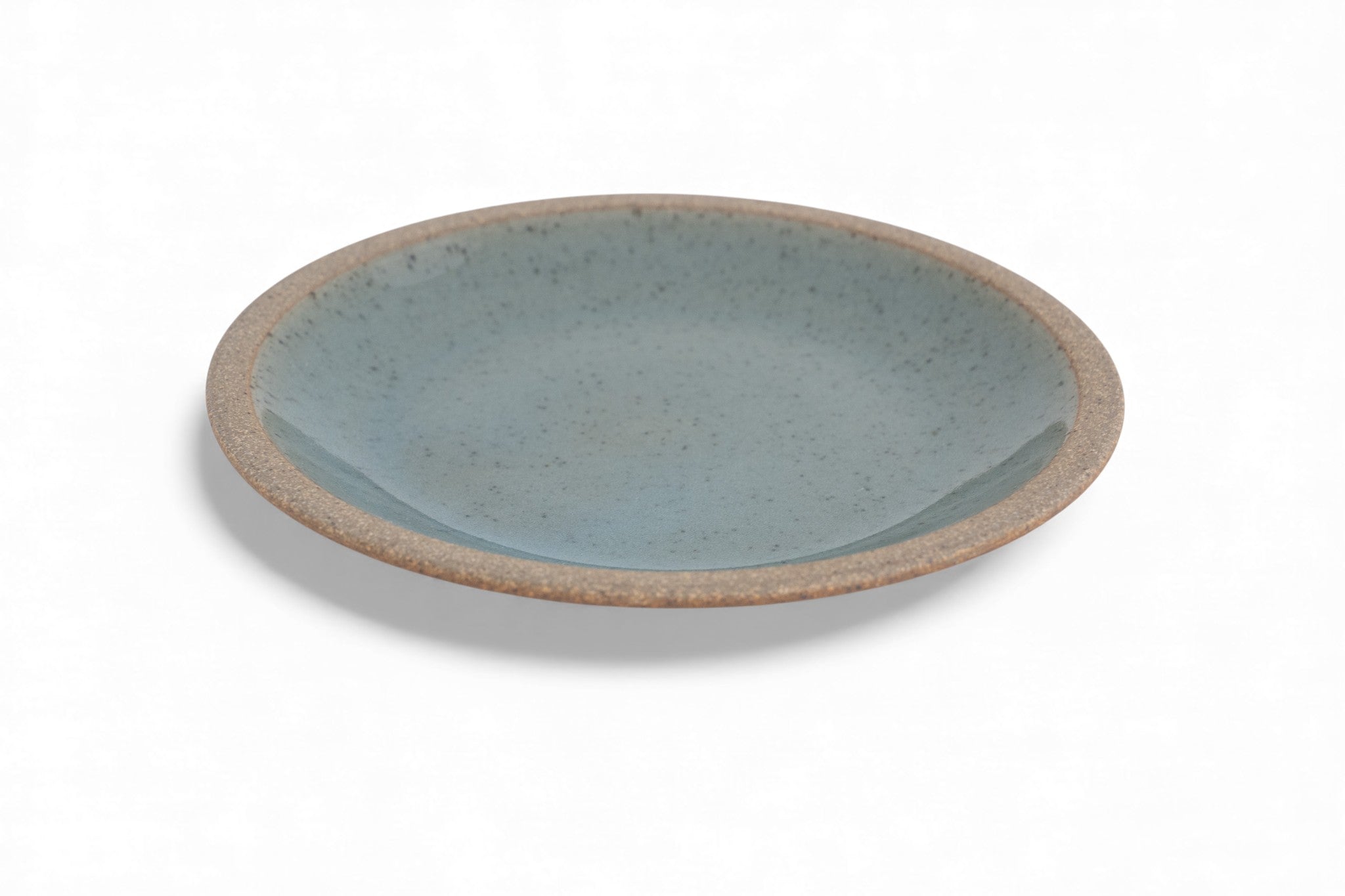 A stoneware dinner plate with a matte raw clay surface and interior glazed in shades of deep celadon green.