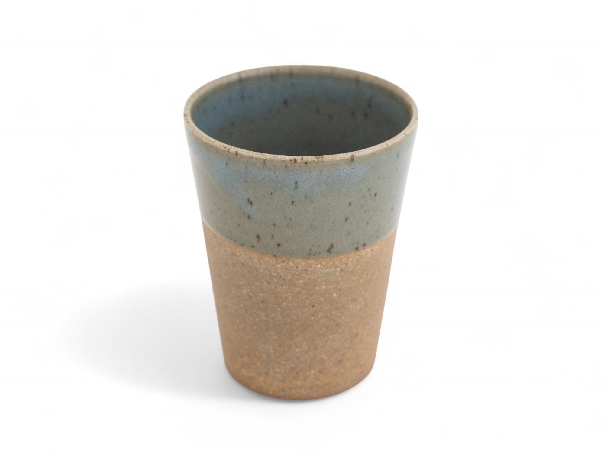 A ceramic beaker with a two-tone color scheme, featuring a matte raw clay surface on the exterior and a glossy glazed deep celadon green interior.