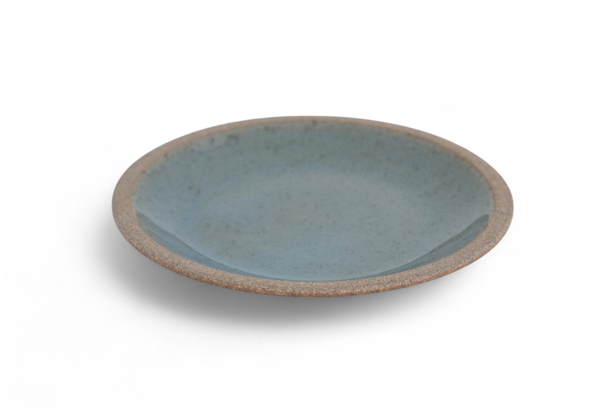 A ceramic dinner plate with a matte raw clay surface and interior glazed in shades of deep celadon green.