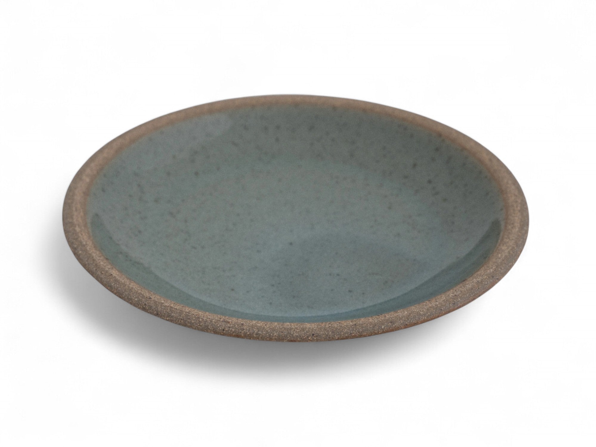 A ceramic side plate with a matte raw clay surface and interior glazed in shades of deep celadon green.