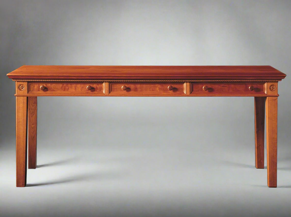 A classic wooden desk with a rectangular tabletop and carved details, including scalloped dentil molding and tapered legs.