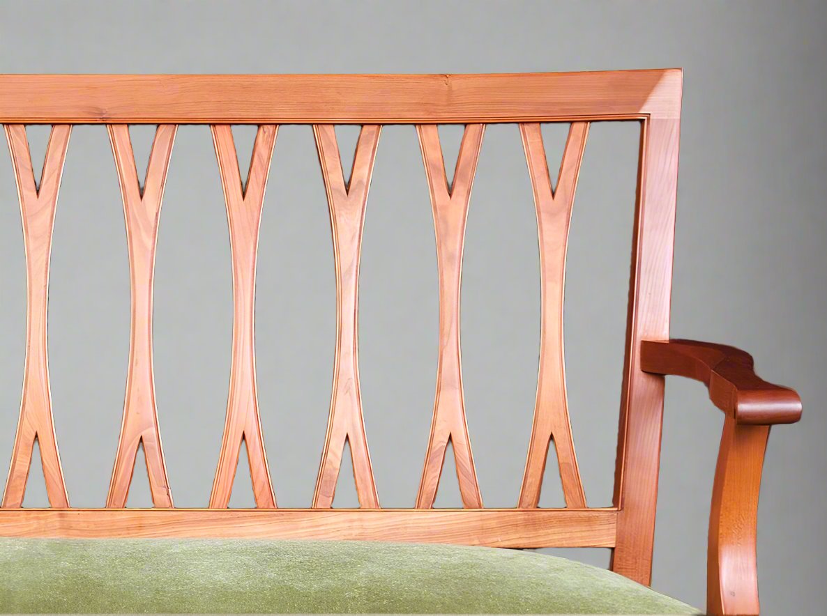 detail of a carved bench with latticed back and upholstered in a green velvet cushion