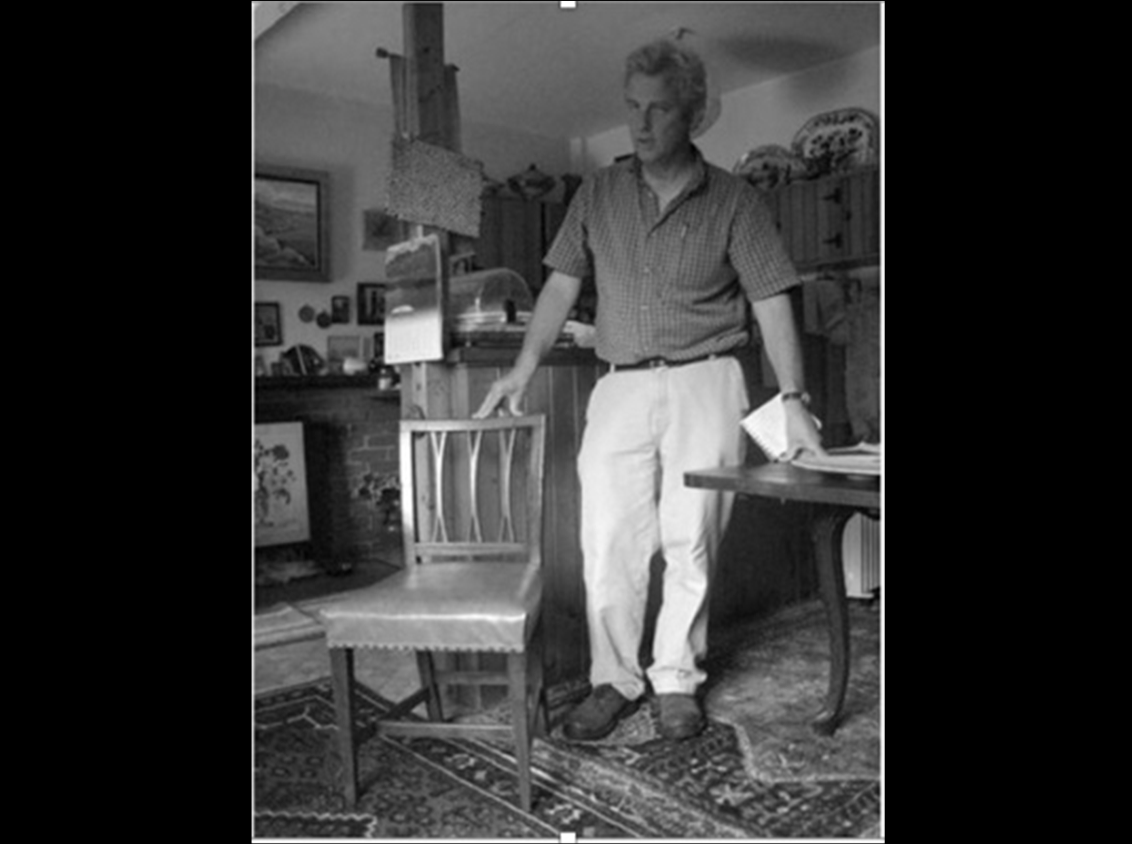 Charles Shackleton standing next to an antique fork-backed dining chair in an old room in Ireland