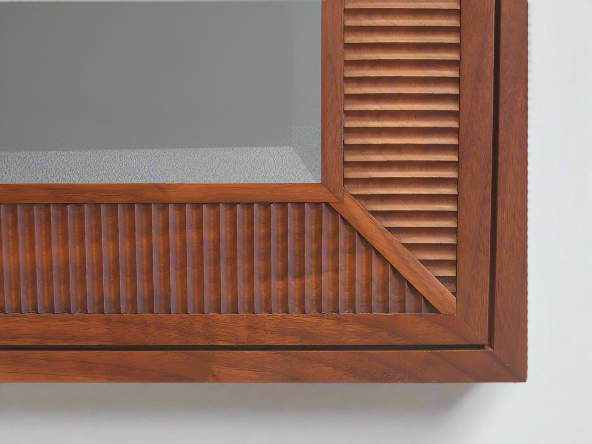 A corner of a modern classic mirror with beveled glass and fluted detailing.