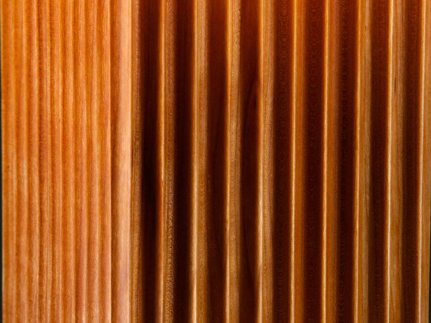 detail of fluted carving in cherry table lamp on black backround