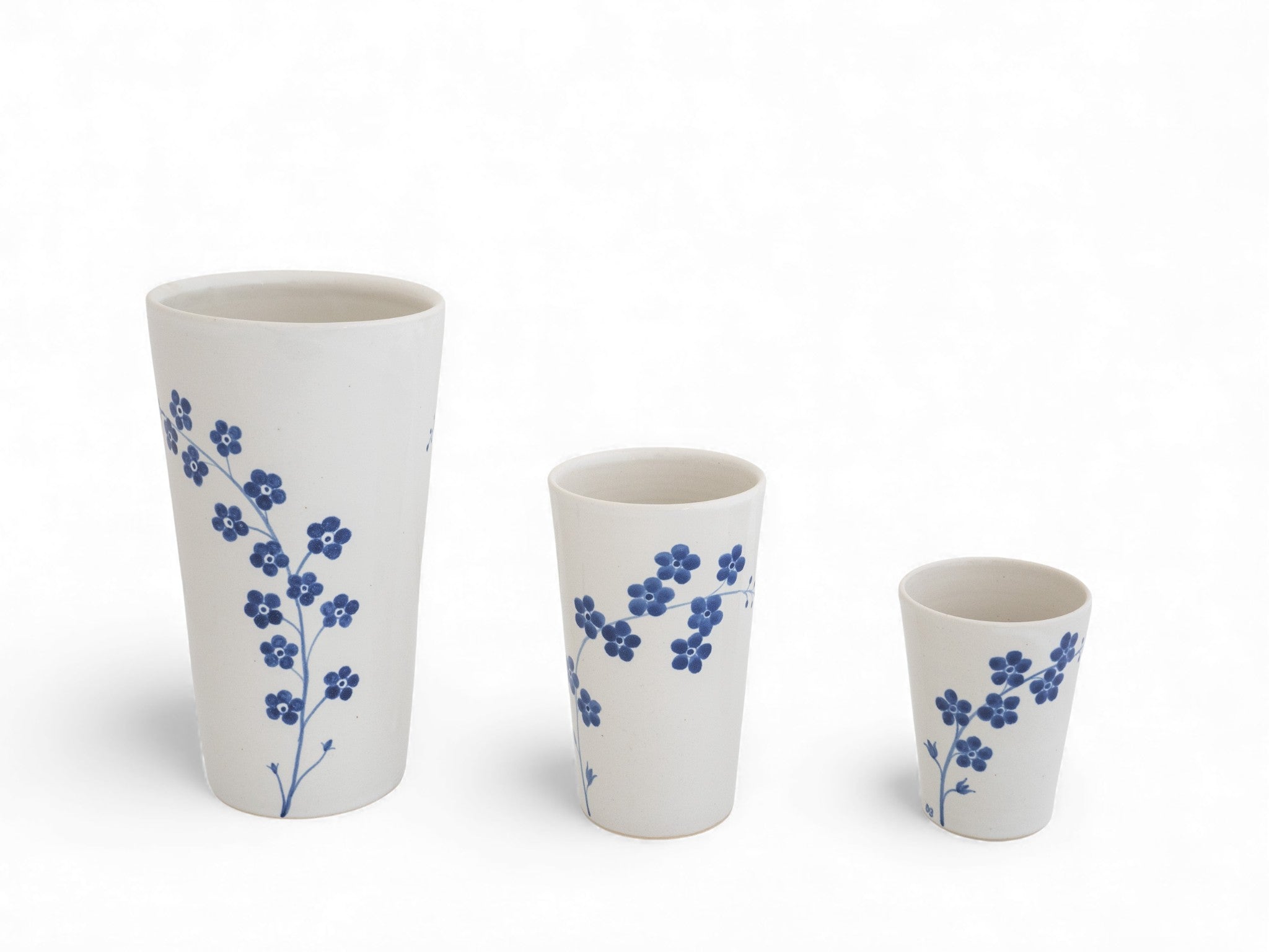 a hand thrown stoneware beaker cup with painted forget-me-not flowers