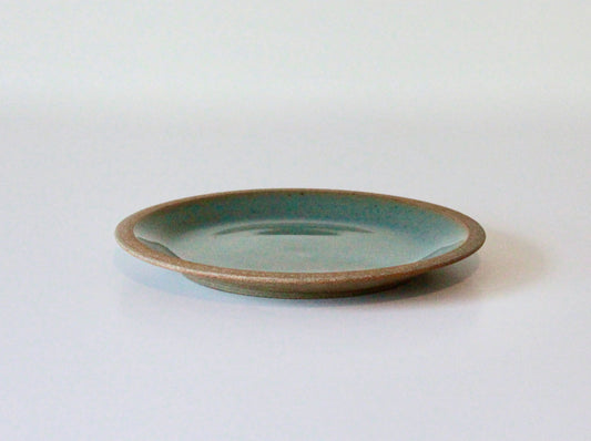 Raw clay plate with blue-green celadon glaze on inside surface