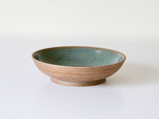 Raw clay pasta plate with blue-green celadon glaze on inside surface