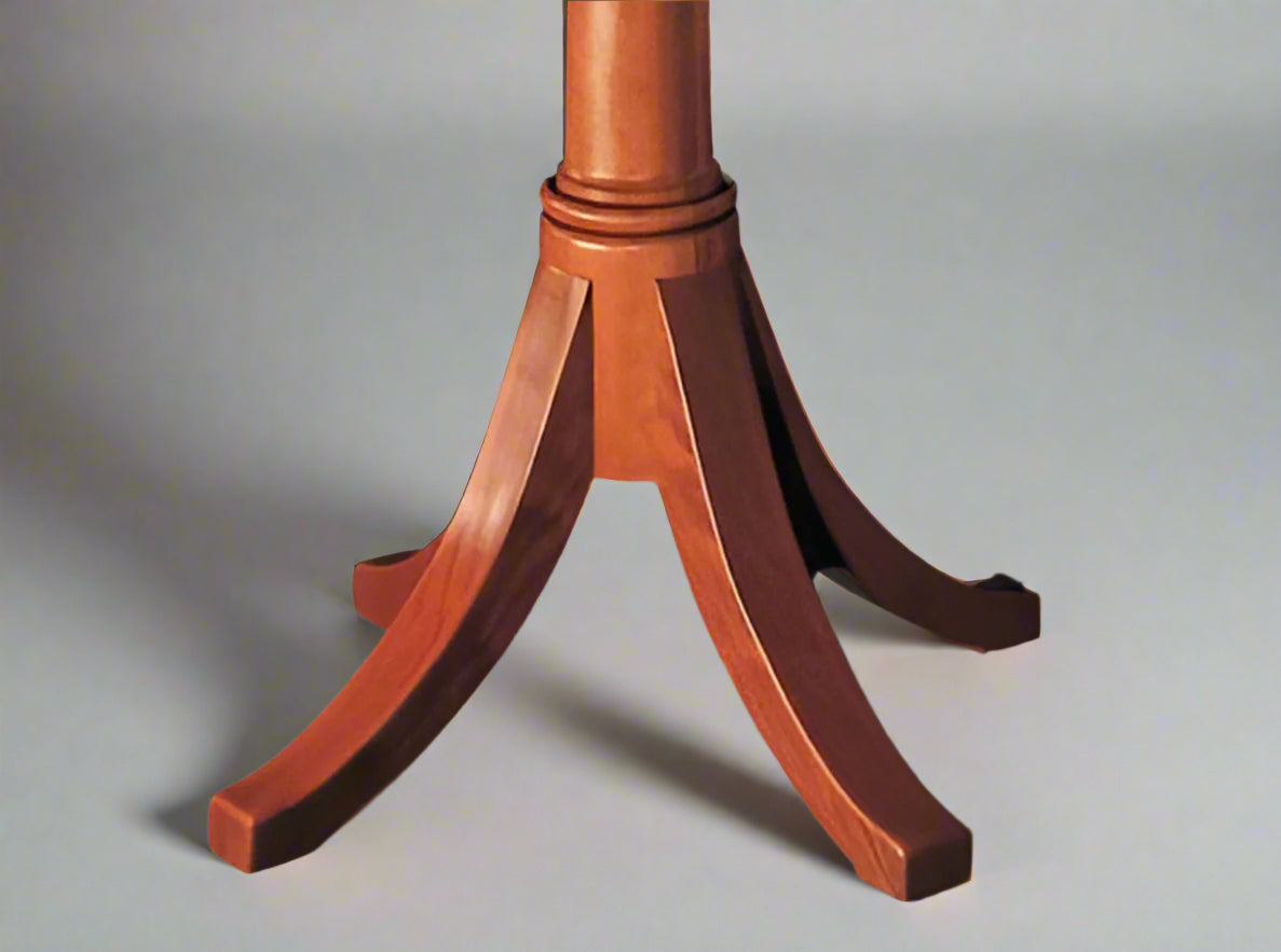 A classic wooden pedestal dining table with hand-carved legs, featuring a thumbnail edge on the top